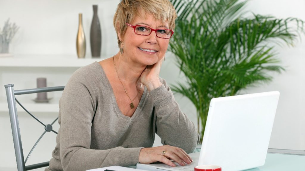 older woman with glasses on her laptop