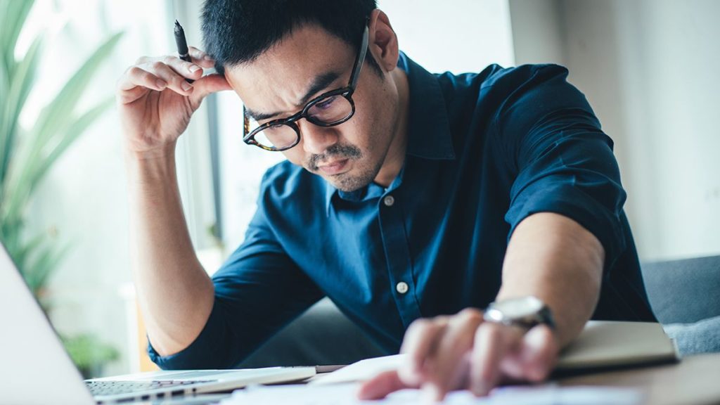 man wearing glasses and blue shirt studying the families first coronavirus response act with focus