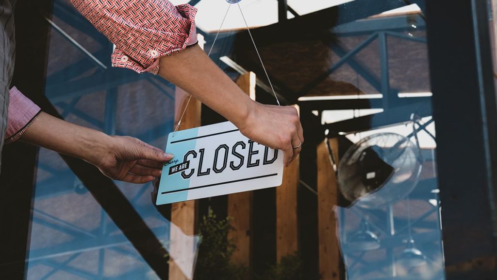 business owner putting up closed sign on a storefront window