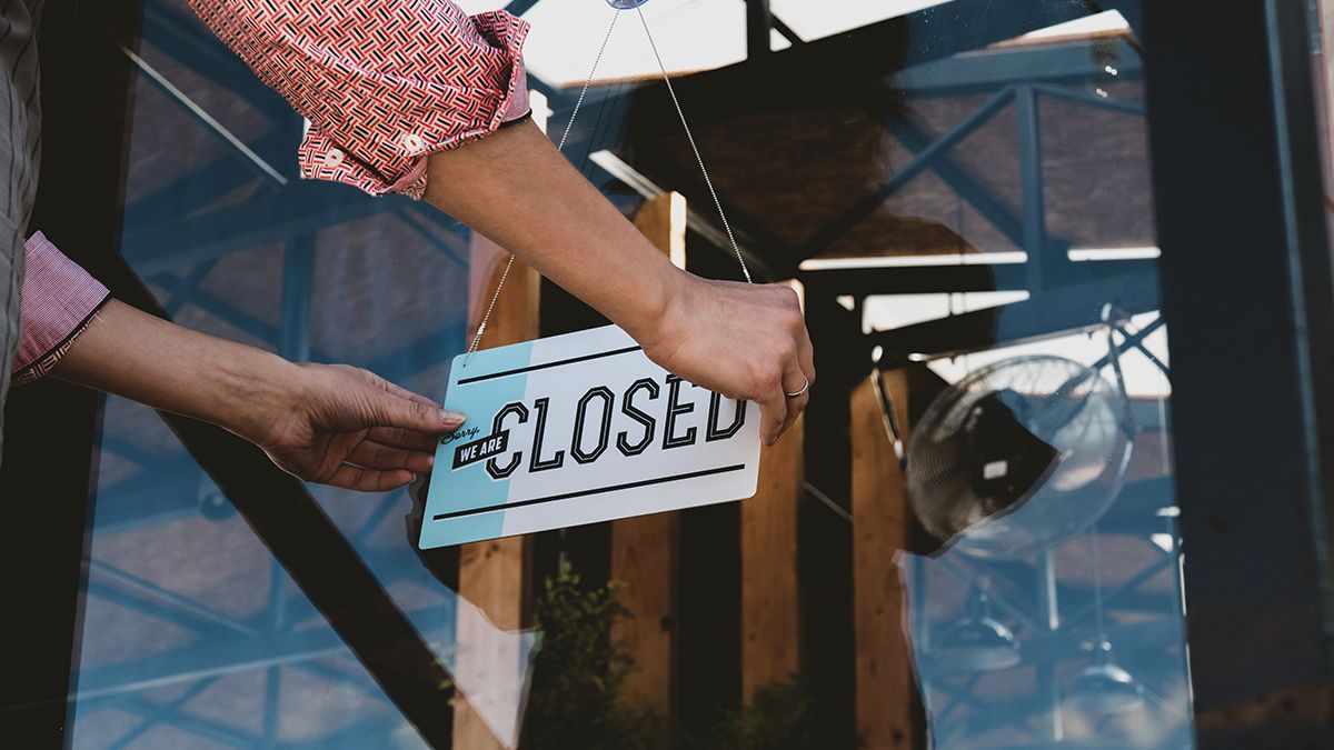 business owner putting up closed sign on a storefront window